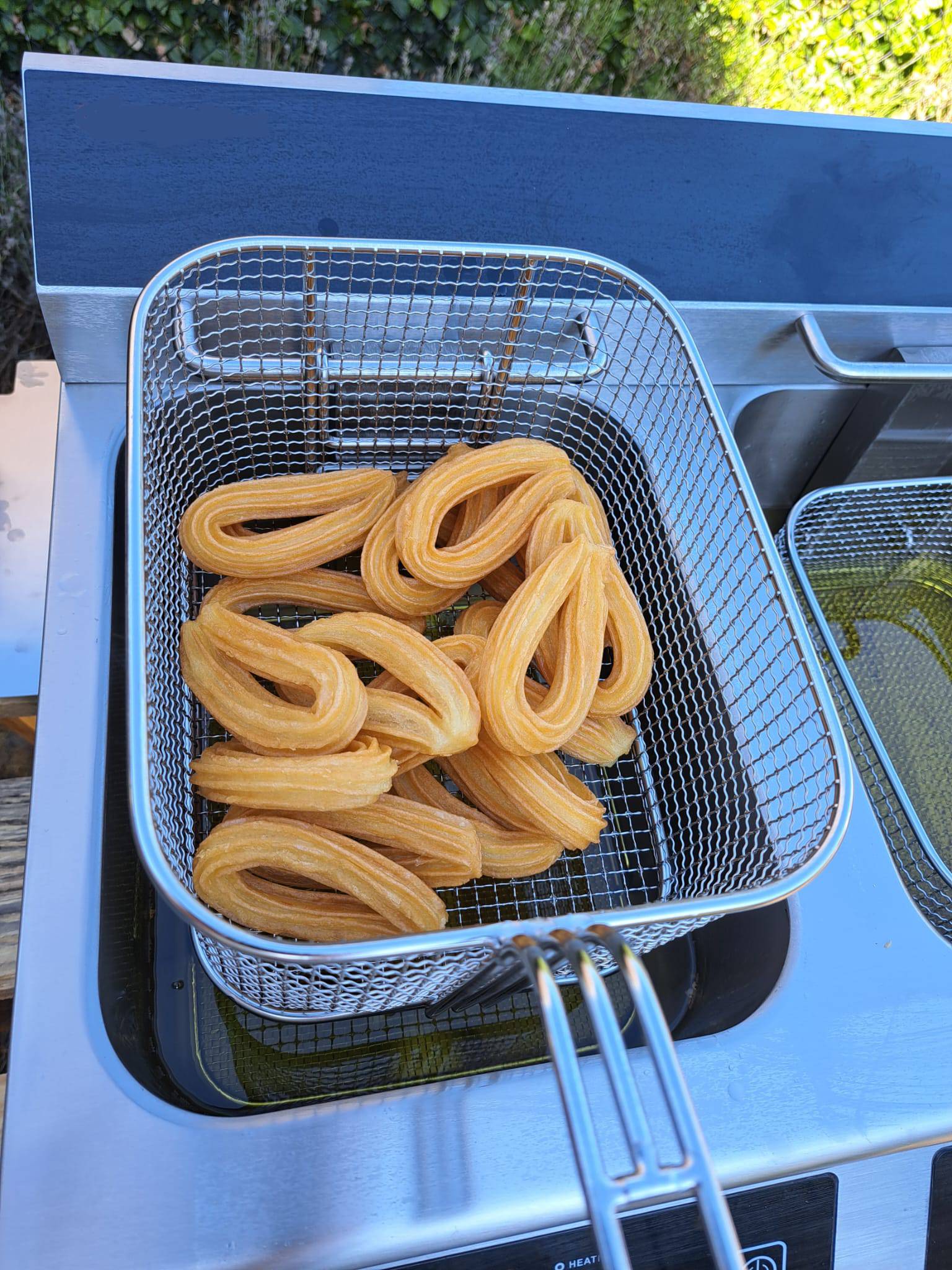 Gouden churros in frituurmand boven frituurpan